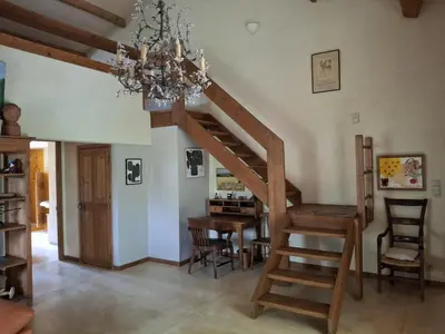 a staircase in a living room with a table and a chandelier at La Maison perchée - Mas de Rousseau in Eyragues
