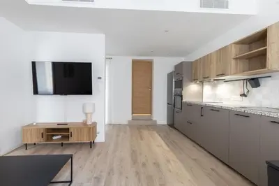 a kitchen with white cabinets and a tv on a wall at Elégance en Luberon - 4 personnes - Central - Wifi in Apt