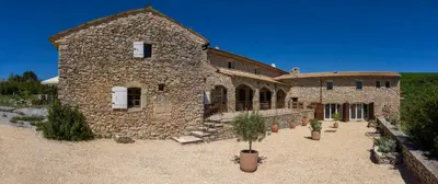 a large stone building with potted plants in front of it at La Buisse in Simiane-la-Rotonde
