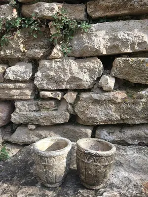 two cement pots in front of a stone wall at La Bergerie Pradel in Le Beaucet
