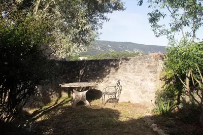 a table and a chair sitting next to a wall at Le charme au centre du village in Ménerbes