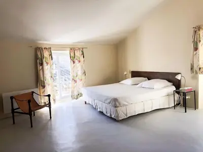 a bedroom with a bed and a chair and a window at Le charme au centre du village in Ménerbes