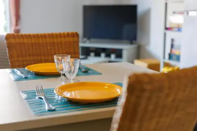 a table with two yellow plates and glasses on it at Bastidon Provençal - Avec piscine partagée in Aubignan