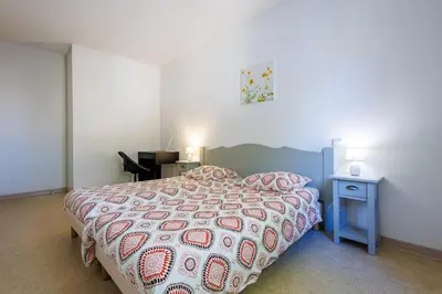 a bedroom with a bed with a red and white comforter at Bastidon Provençal - Avec piscine partagée in Aubignan