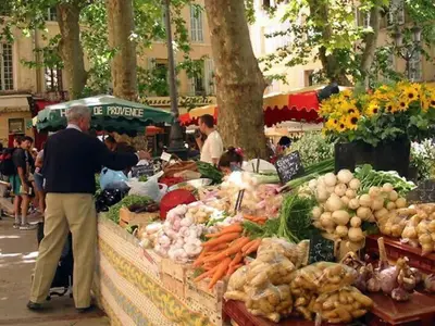 a man standing in front of a vegetable stand at a market at Bel appartement aixois dans le centre historique in Aix-en-Provence