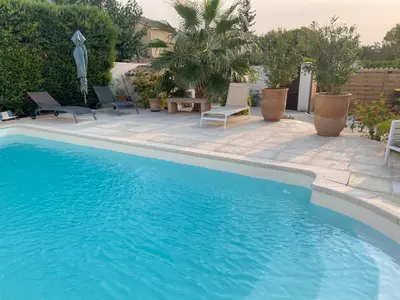 a swimming pool with two chairs and a table at Maison méditerranéenne 130m piscine Vaucluse in Carpentras