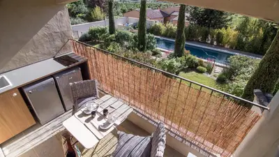 a balcony with a table and chairs and a pool at Le Mas de Cink in Saint-Saturnin-les-Apt