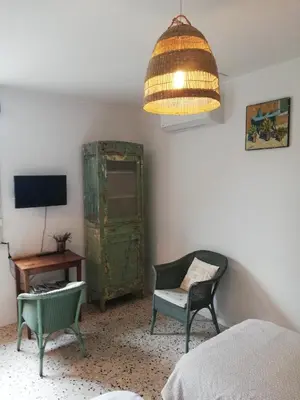 a bedroom with a green cabinet and a chair and a lamp at Gîte de la treille in LʼIsle-sur-la-Sorgue