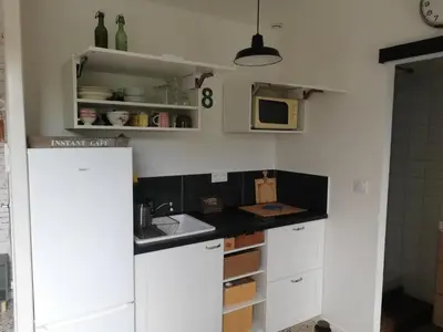 a kitchen with white cabinets and a sink and a microwave at Gîte de la treille in LʼIsle-sur-la-Sorgue