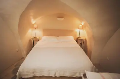 a white bed in a tunnel with two lamps at Ancienne Maison des Gardes in Lourmarin
