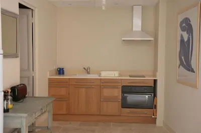 a kitchen with wooden cabinets and a stove top oven at Ancienne Maison des Gardes in Lourmarin