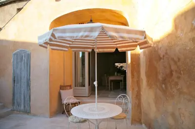 a table with an umbrella on a patio at Ancienne Maison des Gardes in Lourmarin