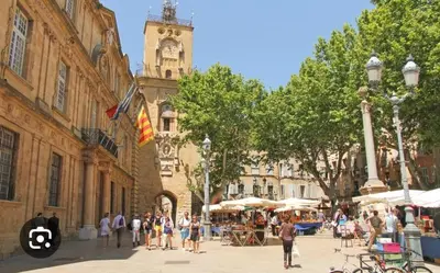 a group of people walking down a street with a clock tower at Le Mistral Studio au cœur du centre historique in Aix-en-Provence