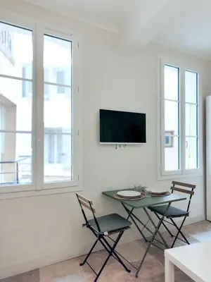 a living room with a table and two chairs and a tv at Le Mirabeau studio au cœur du centre historique - 2eme étage in Aix-en-Provence
