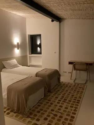 a bedroom with two beds and a desk and a television at Le Jardin des Graminées in Cabrières-dʼAvignon