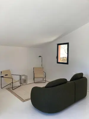 a living room with a green couch and a chair at Le Jardin des Graminées in Cabrières-dʼAvignon