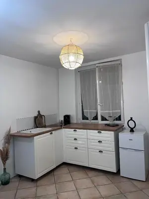 a kitchen with white cabinets and a chandelier at 2 rooms very well located in L'Isle-sur-la-Sorgue in LʼIsle-sur-la-Sorgue