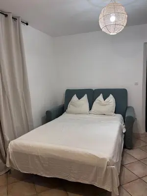 a bed with white sheets and a blue headboard at 2 rooms very well located in L'Isle-sur-la-Sorgue in LʼIsle-sur-la-Sorgue