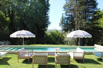 a group of chairs and umbrellas next to a pool at Quiet Provencal bastide with pool close Lourmarin in Lauris