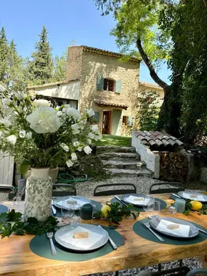 a wooden table with plates and glasses and a house at Quiet Provencal bastide with pool close Lourmarin in Lauris