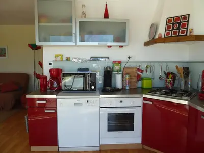 a kitchen with red cabinets and a white microwave at Iris Caromb in Caromb