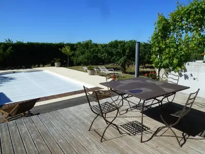 a table and chairs on a deck next to a pool at Iris Caromb in Caromb