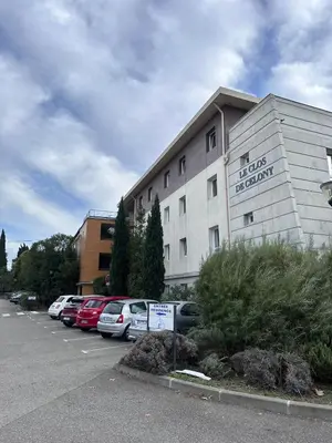 a building with cars parked in a parking lot at Le Clos D'AIX Studio 108 in Aix-en-Provence
