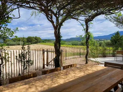 a wooden bench in front of a fence with a tree at La Bastide des Amis in Caromb