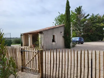 a fence in front of a house with a car at La Bastide des Amis in Caromb