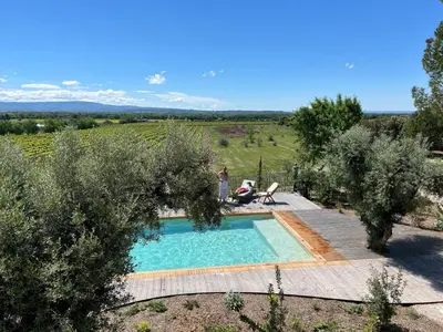 a person standing next to a swimming pool in a yard at La Bastide des Amis in Caromb