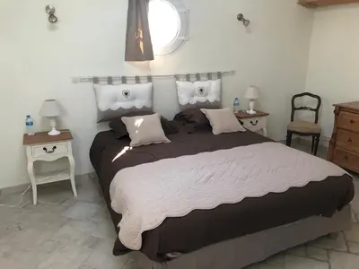 a bedroom with a large bed with two tables and a window at Maison d'hôte en Provence avec petit déjeuner in Mollégès