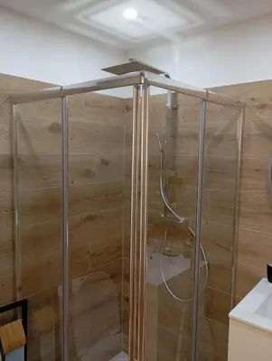 a shower in a bathroom with wooden walls at studio in Morières-lès-Avignon