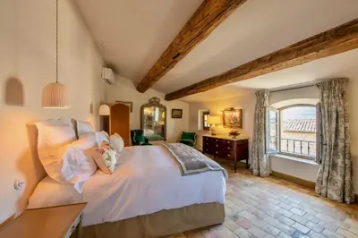 a bedroom with a bed and a desk and a window at La Bastide in Oppède