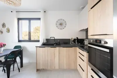 a kitchen with wooden cabinets and a black counter top at La maison d'Alice - Calme - Climatisation - Parking privatif in Velaux