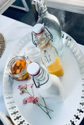 a white plate with a bottle of orange juice and a candle at Casa Regina - Spacieux appartement près de la Sorgue in LʼIsle-sur-la-Sorgue