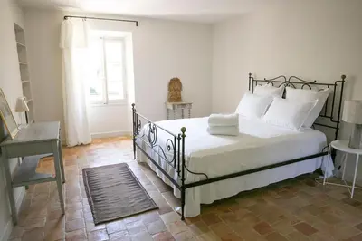 a bedroom with a bed with white pillows and a window at Le mas provençal d'Aurélie in Carpentras