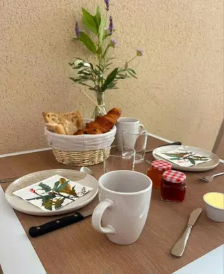 a table with plates and cups and a basket of bread at L'Orée du Ventoux - Crillon-le-Brave in Crillon-le-Brave