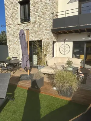a patio with a couch and an umbrella at Chambres d'hôte in Châteauneuf-de-Gadagne