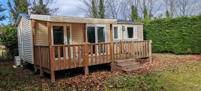 a wooden cabin with a large deck in a field at Mobilhome 6 personnes in Cheval-Blanc