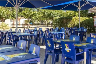 a group of blue tables and chairs with an umbrella at Mobilhome 6 personnes in Cheval-Blanc