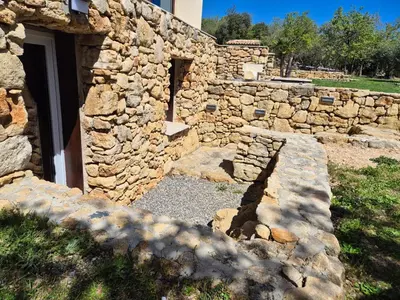 a stone building with a door and a stone wall at Lou damisello - Villa moderne in Viens