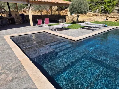 a swimming pool in a yard with chairs and a house at Lou damisello - Villa moderne in Viens