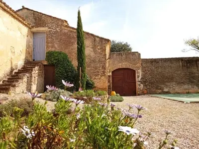 a stone building with a door and some flowers at Le Rocan Roux in Aubignan