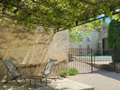 two chairs sitting next to a fence with a pool at Le Rocan Roux in Aubignan