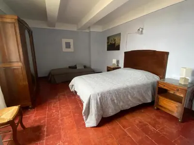 a bedroom with a bed and a table in a room at Le Rocan Roux in Aubignan
