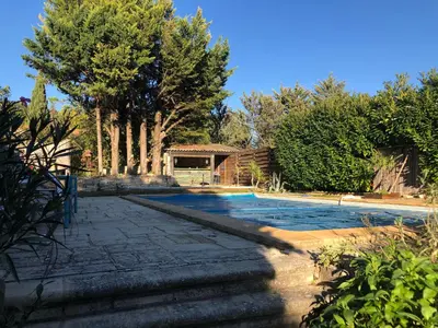 a swimming pool in a yard with trees and a house at Cabane bambou in Apt