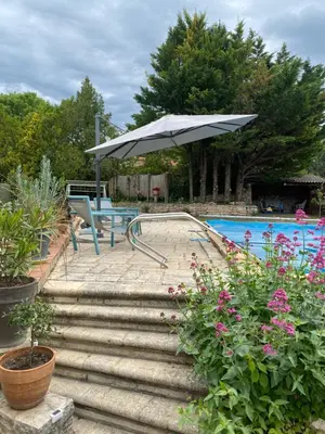 a patio with a table and an umbrella next to a pool at Cabane bambou in Apt