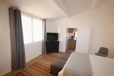 a bedroom with a bed and a tv and a window at Appartement Quartier Mazarin in Aix-en-Provence