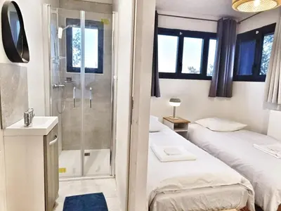 a bathroom with two beds and a shower at Au sommet des Ocres et des Bois - Maison T3 & Parking in Roussillon