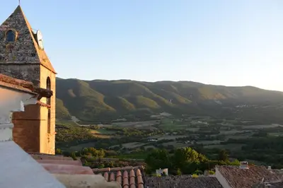 a view of a church with mountains in the background at Grande maison de village - solarium et terrasse in Saint-Martin-de-Castillon